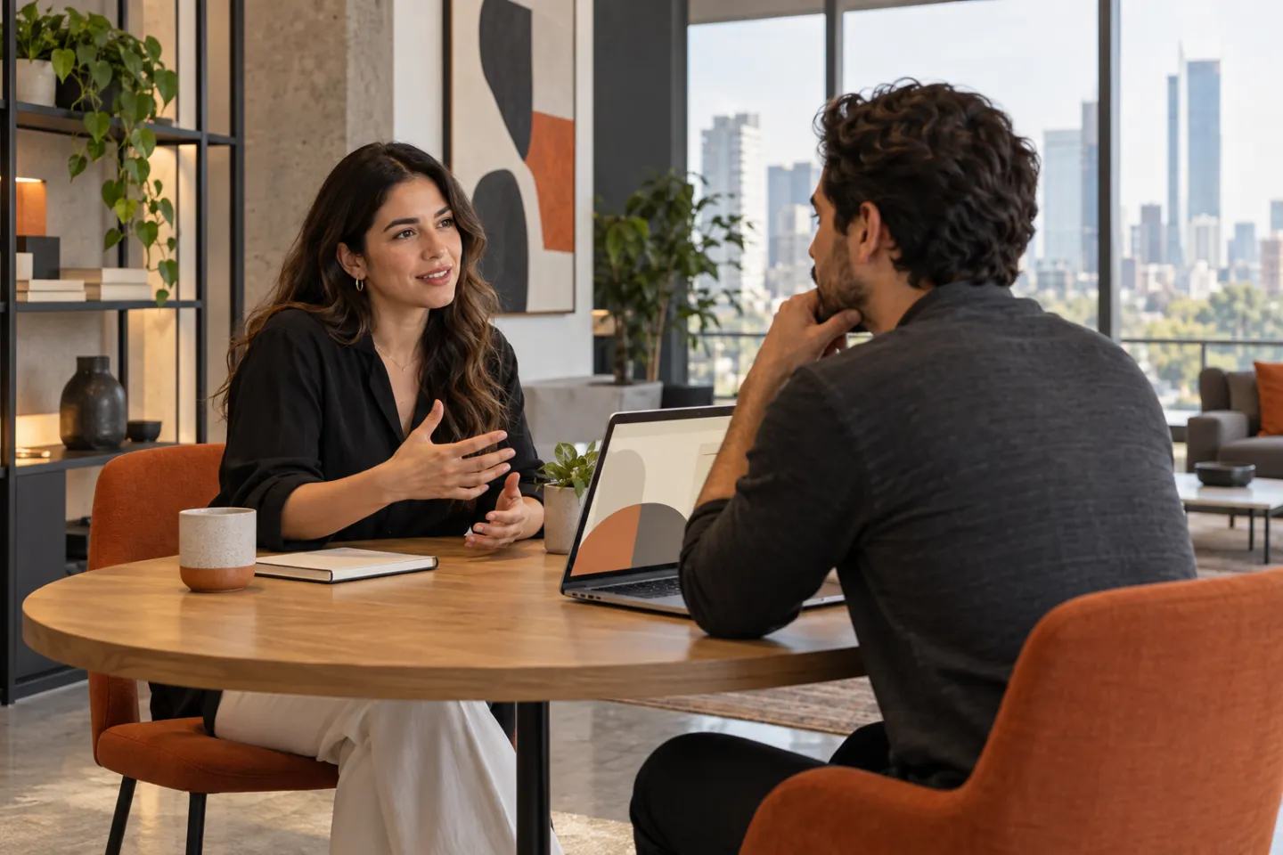 Dos colegas conversando en una mesa de trabajo luminosa.